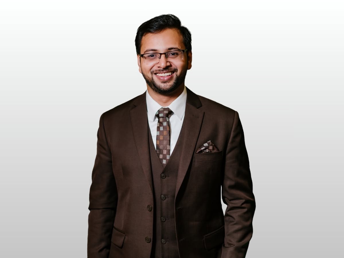 Jaki Osman, founder of Grow Biz Locally, wearing a dark suit and smiling